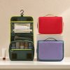 Custom hanging toiletry bag in olive green opened to three tiers beside red and lilac versions, Malaysia